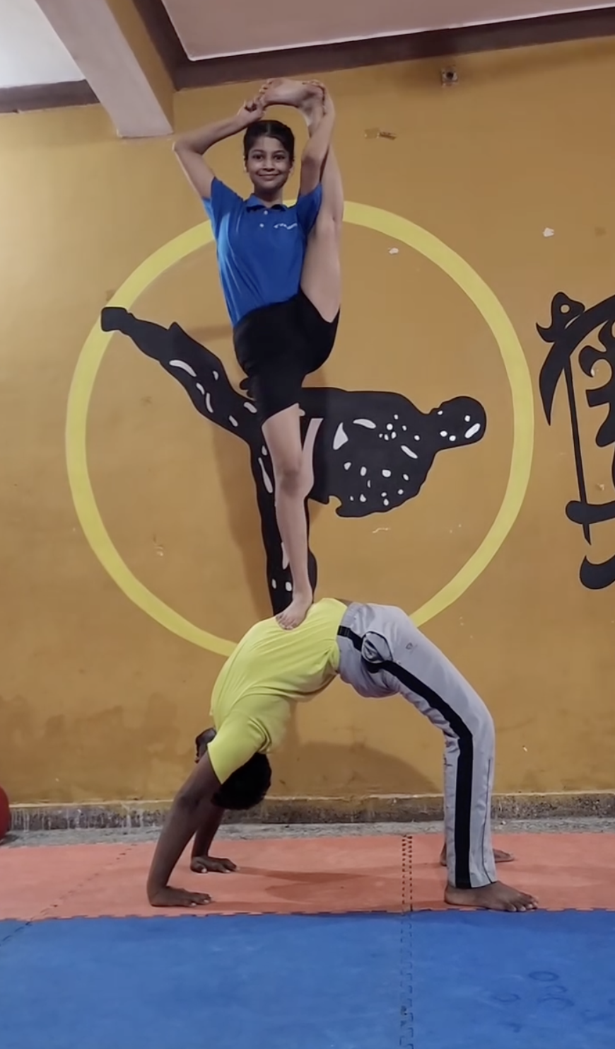Two young students performing acro yoga